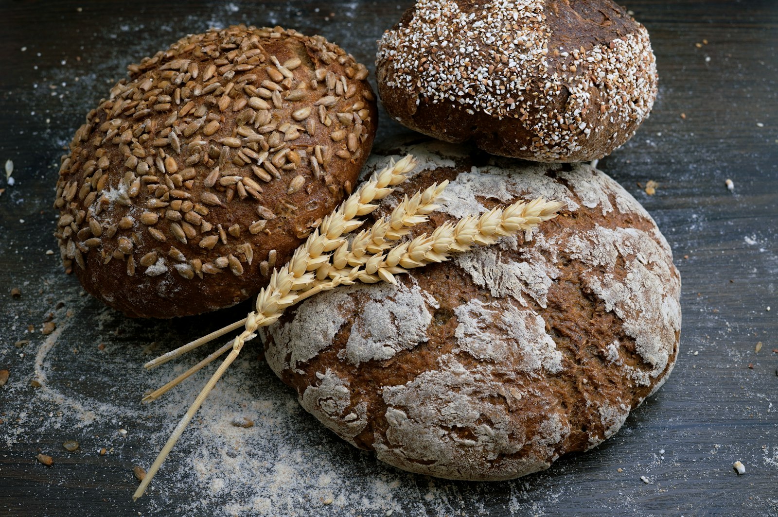 Rustic seeded loaves dusted with flour on a dark wooden table (placeholder photo)