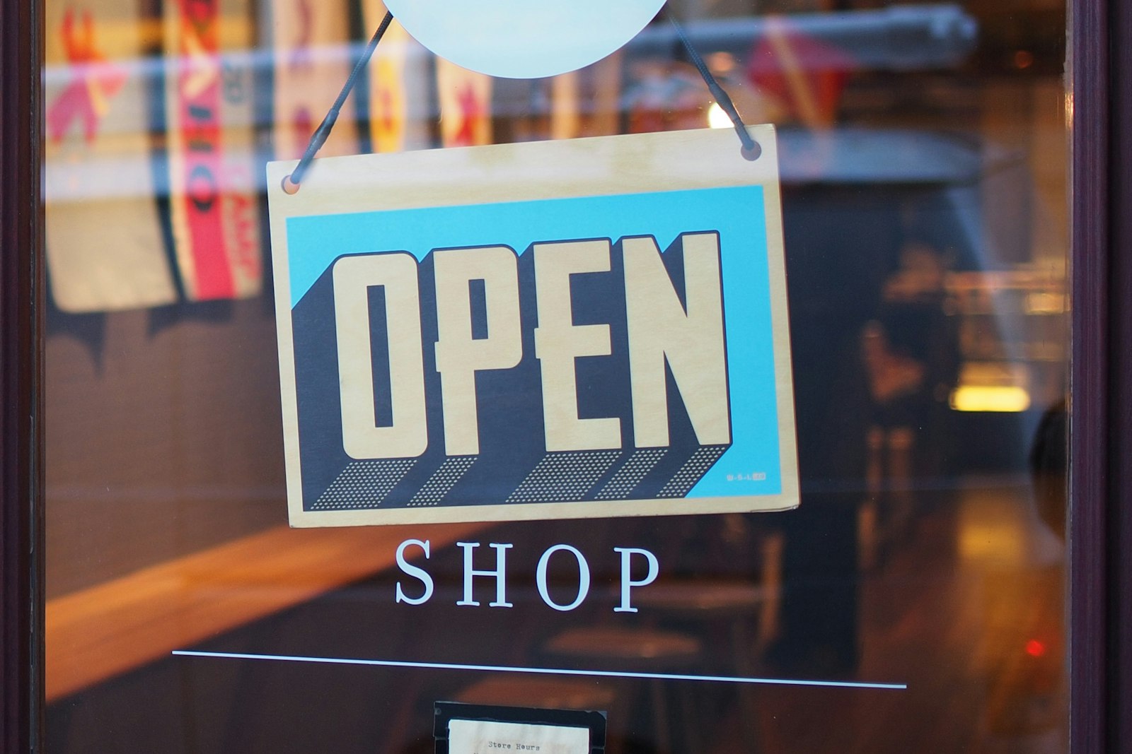 A hand-painted OPEN sign hanging in a shop door (placeholder photo)