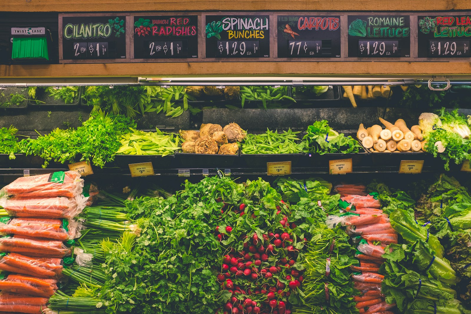 A produce cooler stacked with fresh greens under hand-lettered chalkboard signs (placeholder photo)